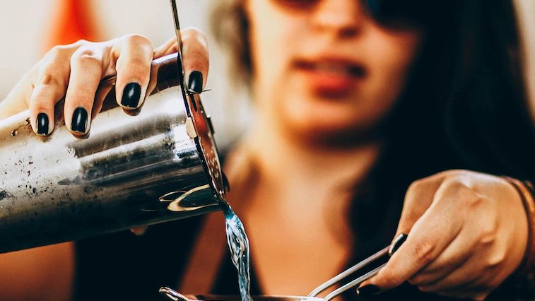 A female bartender pours a cocktail